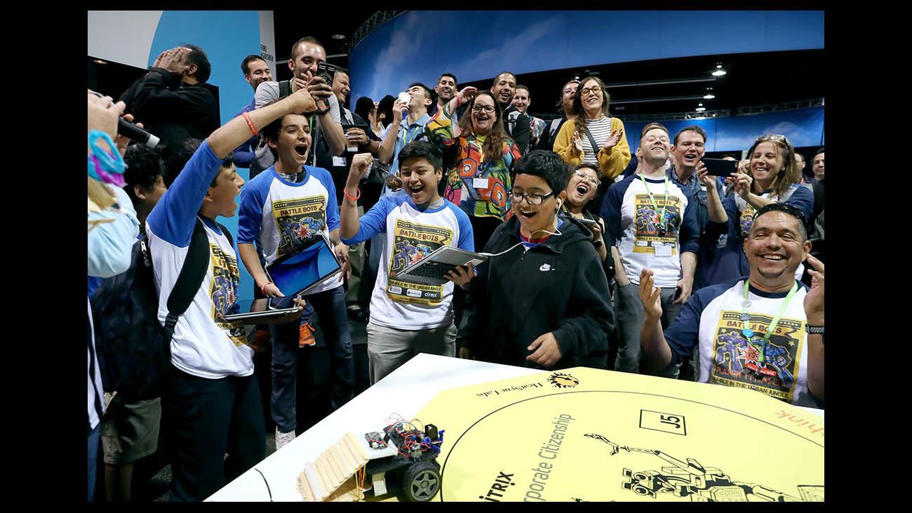 Ensign Intermediate School eighth-graders Jesus Ceja, left, and Emanuel Arista, center right, celebrate their victory in the finals of the Battle Bots competition Tuesday at the Anaheim Convention Center.