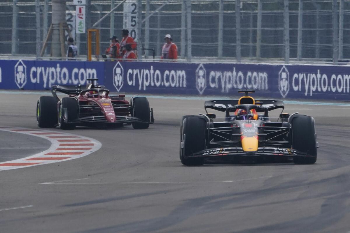 Max Verstappen races ahead of Charles Leclerc on a Grand Prix track.