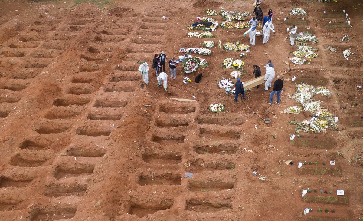 Cemetery workers in protective clothing bury three victims