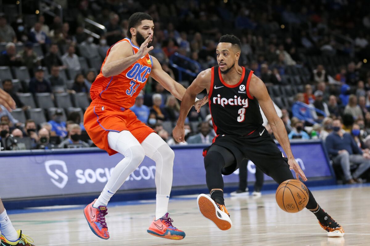 Portland Trail Blazers guard CJ McCollum, right, drives against Oklahoma City Thunder forward Kenrich Williams in the first half of an NBA basketball game Monday, Jan. 31, 2022, in Oklahoma City. (AP Photo/Nate Billings)