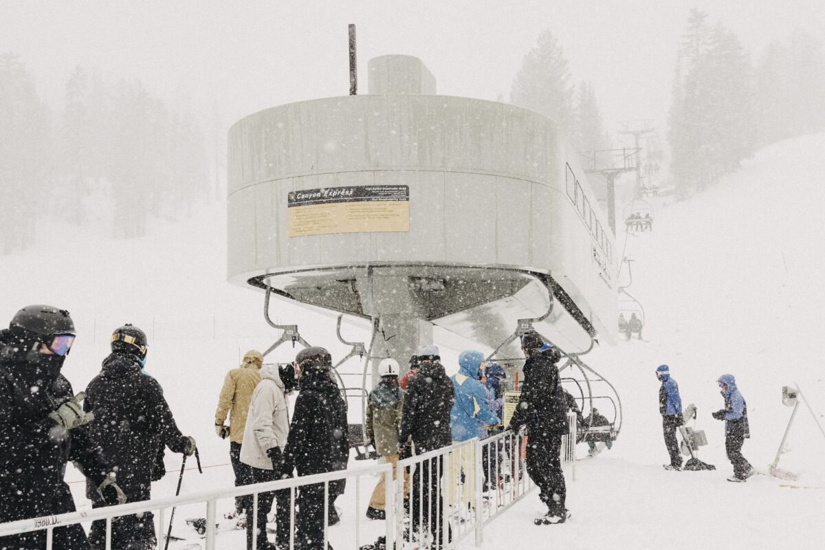 People line up at a chairlift in heavy snow