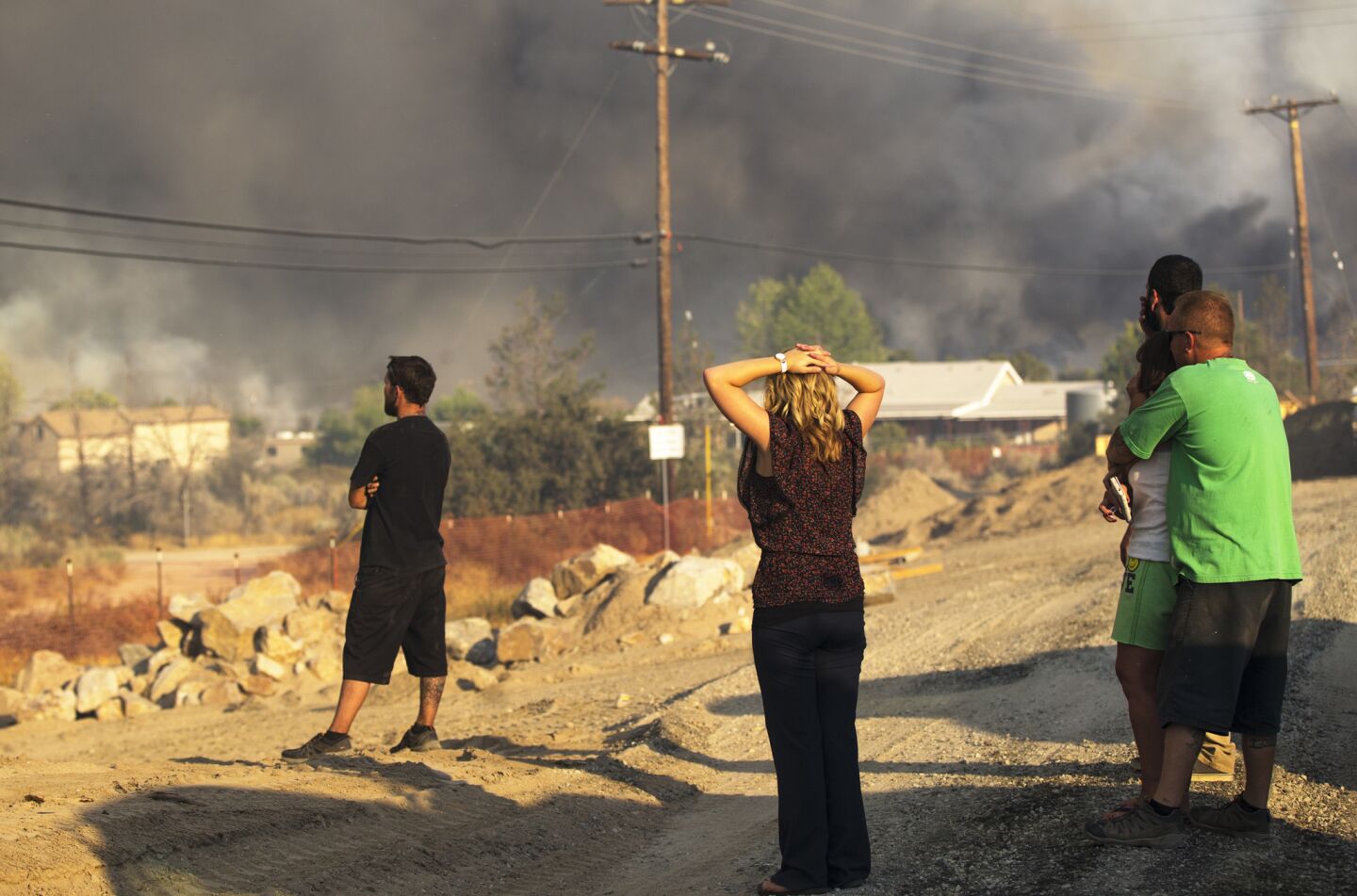 Residents watch in despair as the Blue Cut fire burns homes on the hillside off Highway 138 in Summit Valley, California.