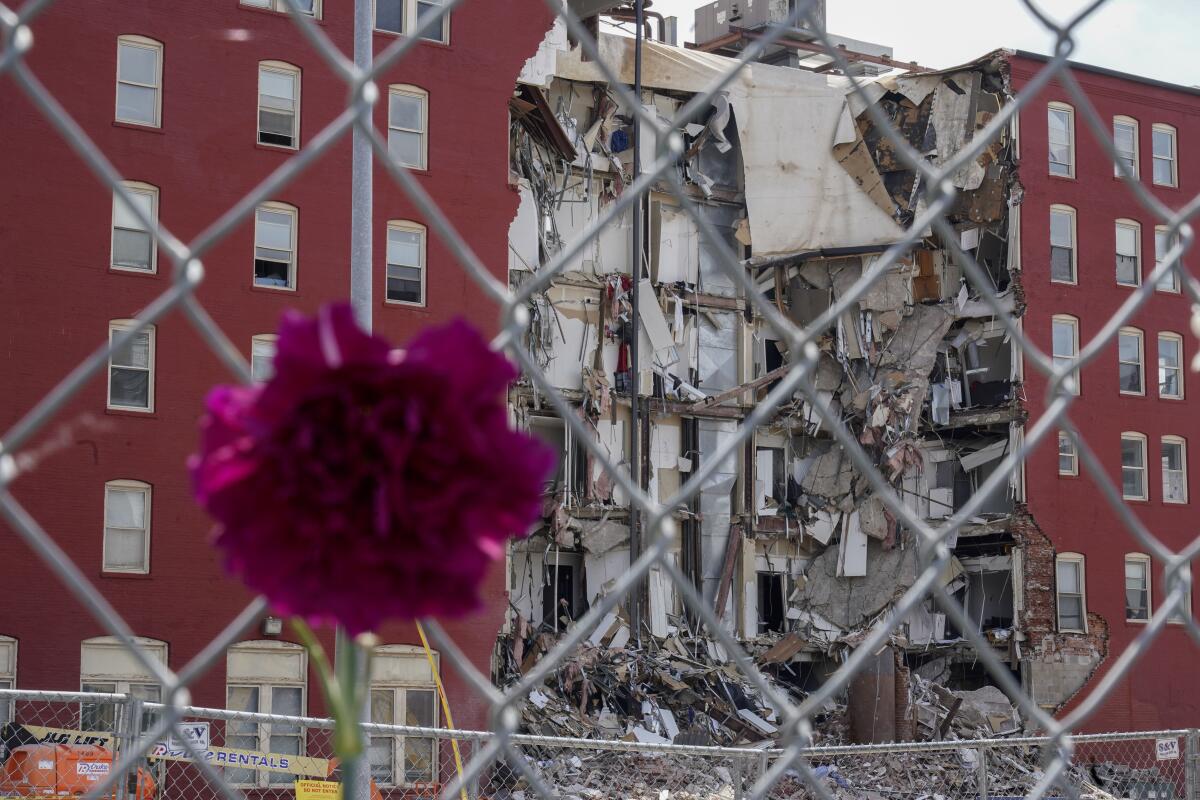 Una flor colgada en una valla frente a un edificio colapsado en Davenport, Iowa,