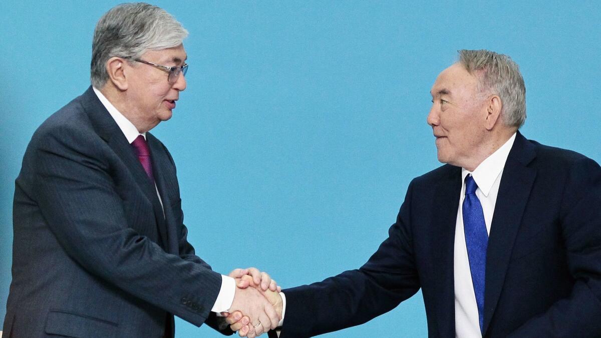 Kazakh President Kassym-Jomart Tokayev, left, shakes hands with his powerful predecessor, Nursultan Nazarbayev, during a congress of the ruling Nur Otan party in Nur-Sultan, Kazakhstan, on April 23, 2019.