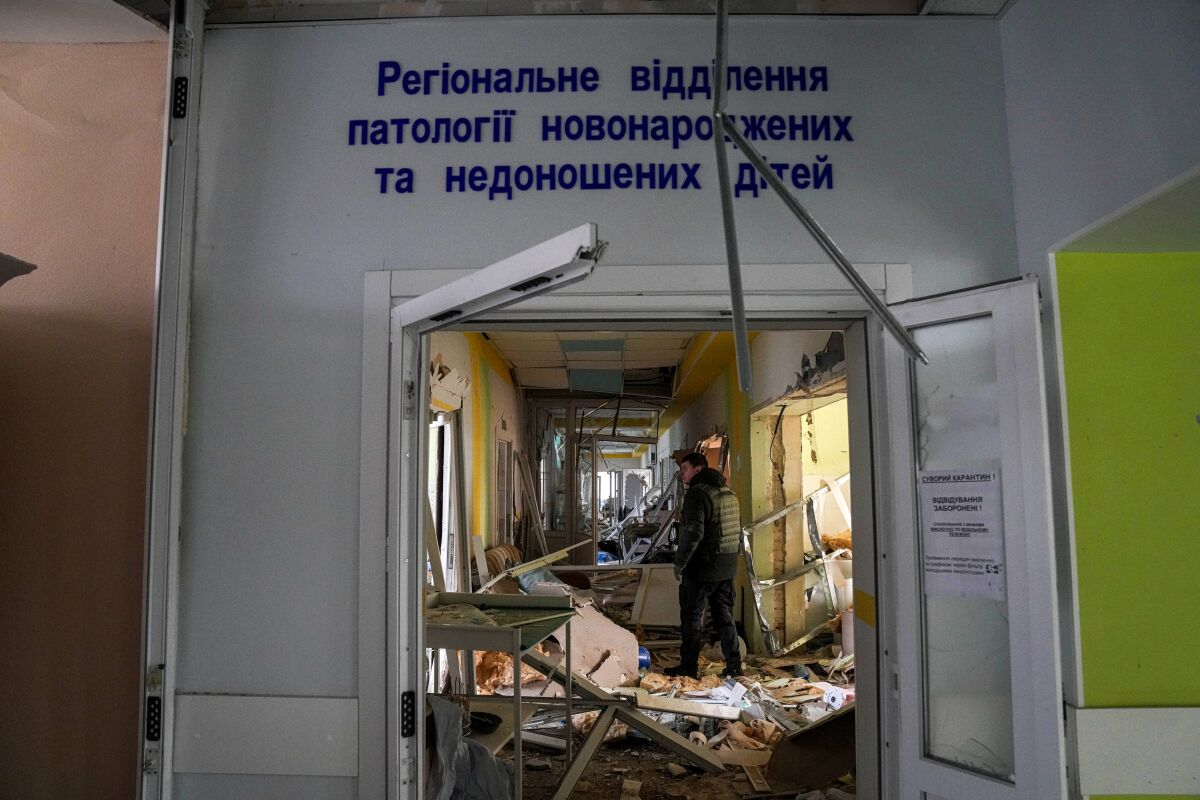 A man stands in a hallway with destruction around him