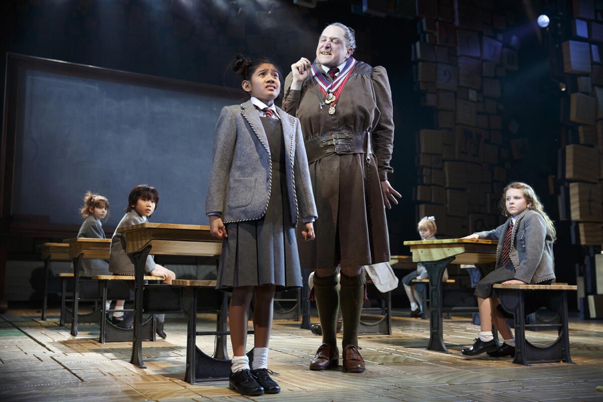 An adult in a severe costume lectures a costumed child in the Broadway production of "Matilda the Musical."
