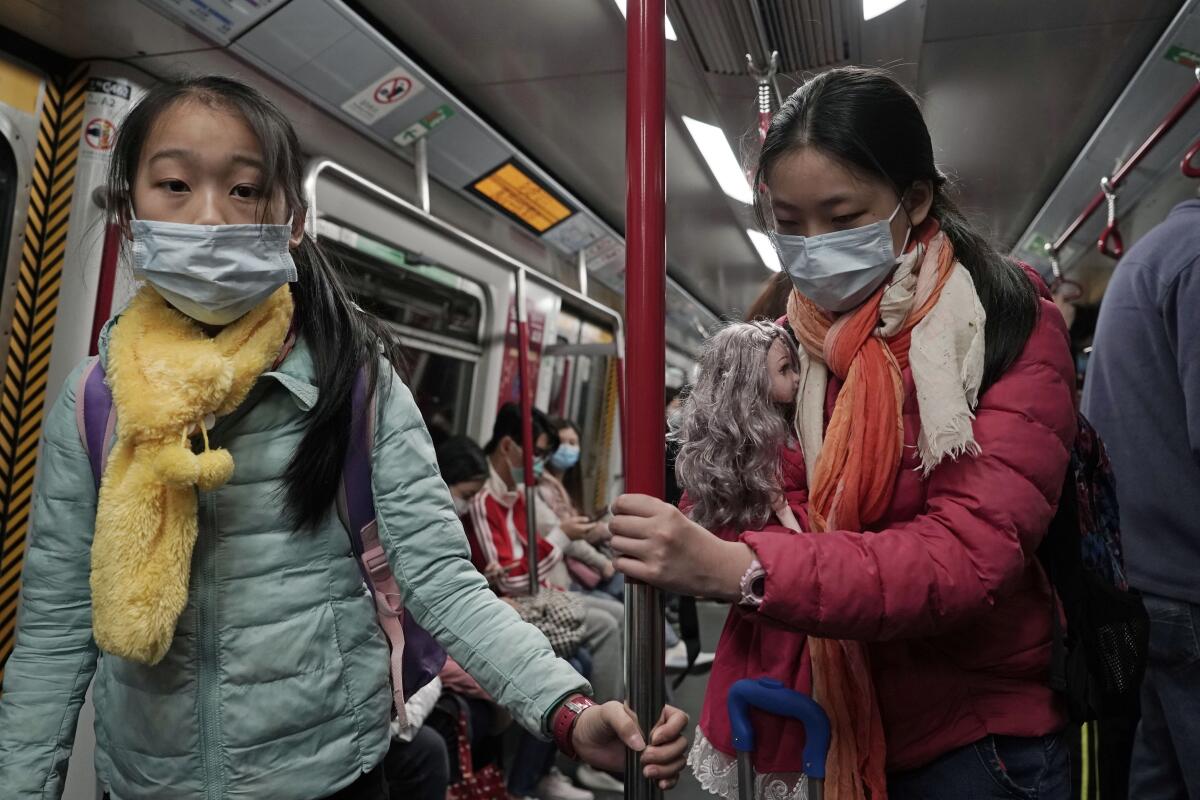 Girls with face masks ride the subway in Hong Kong.