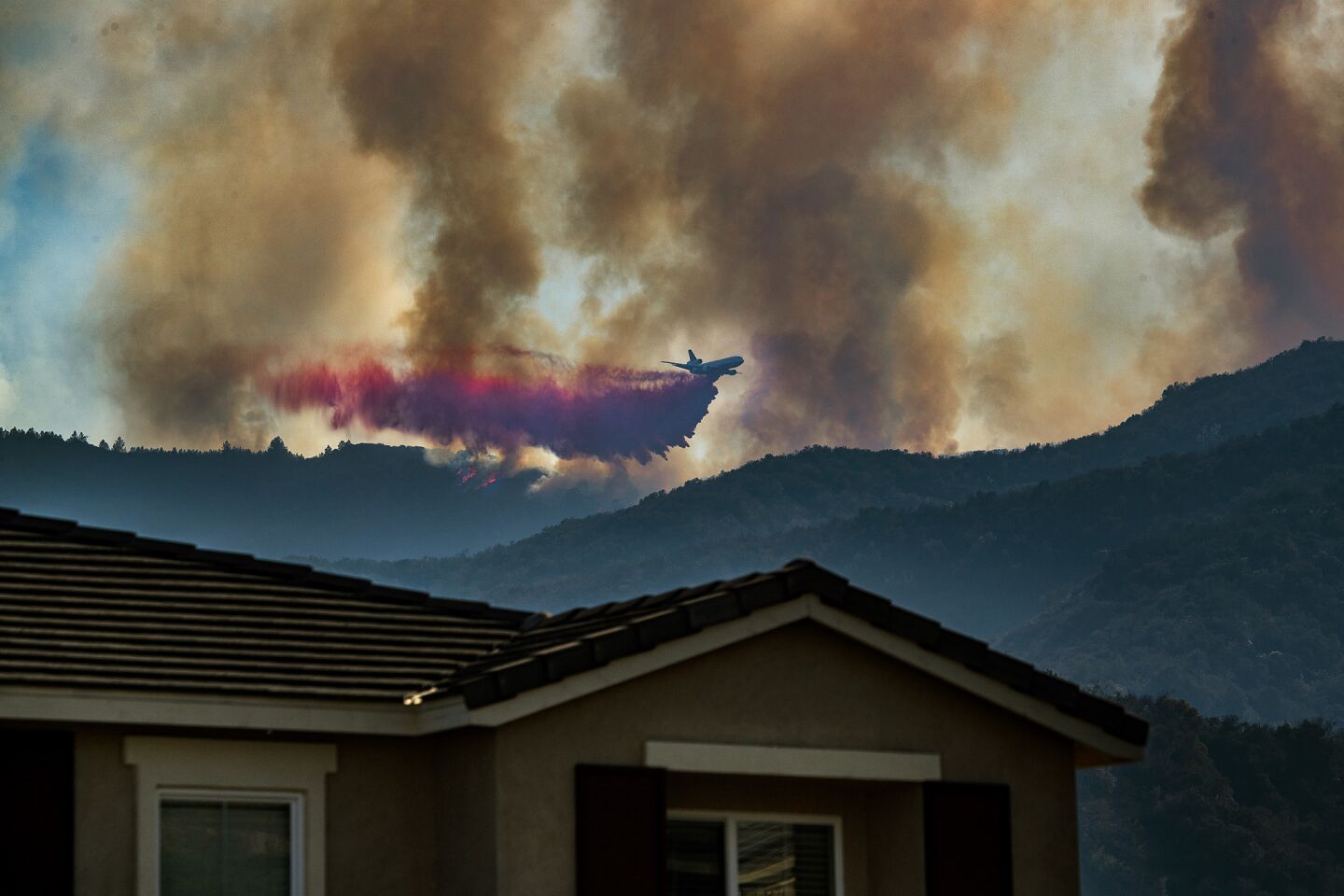A plane drops fire retardant on the Holy fire burning in Cleveland National Forest above a home in Lake Elsinore on Aug. 7.