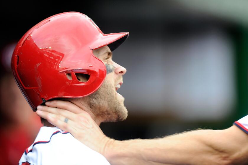 Washington Nationals outfielder Bryce Harper is grabbed by teammate Jonathan Papelbon during the eighth inning against Philadelphia on Sunday.