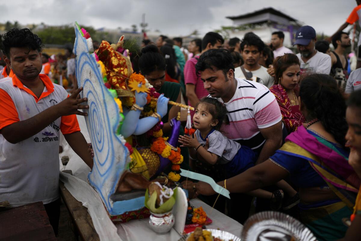 Devotees offer prayers before immersing an idol of elephant-headed Hindu god Ganesha in the Arabian Sea, during the ten days long Ganesh Chaturthi festival in Mumbai, India, Sunday, Sept. 4, 2022. (AP Photo/Rafiq Maqbool)