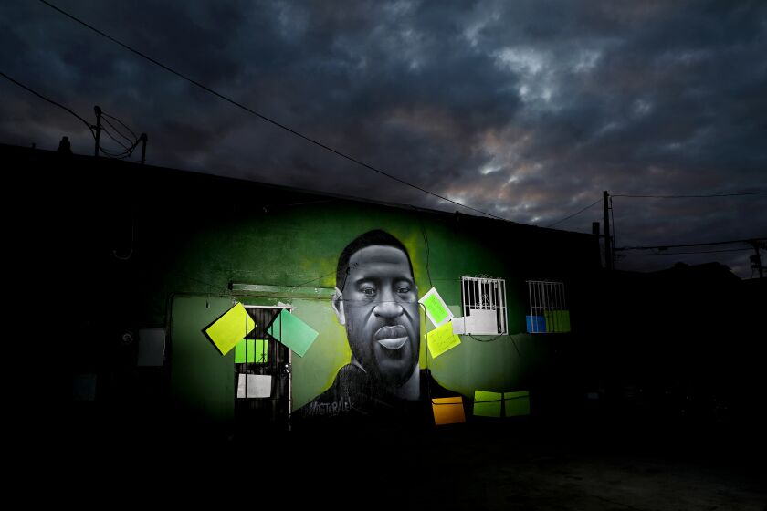 A mural of George Floyd by artist Misteralek is seen at dusk at Wilmington Ave. and 105th St. in Watts.