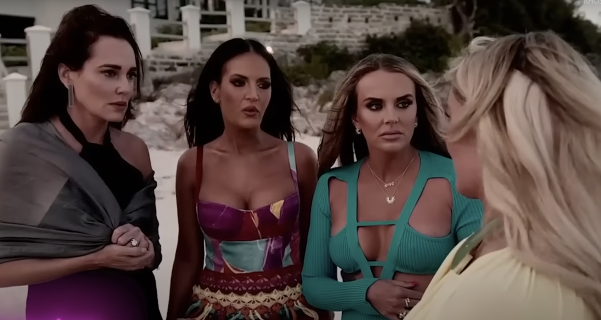 Four women looking shocked on a beach.