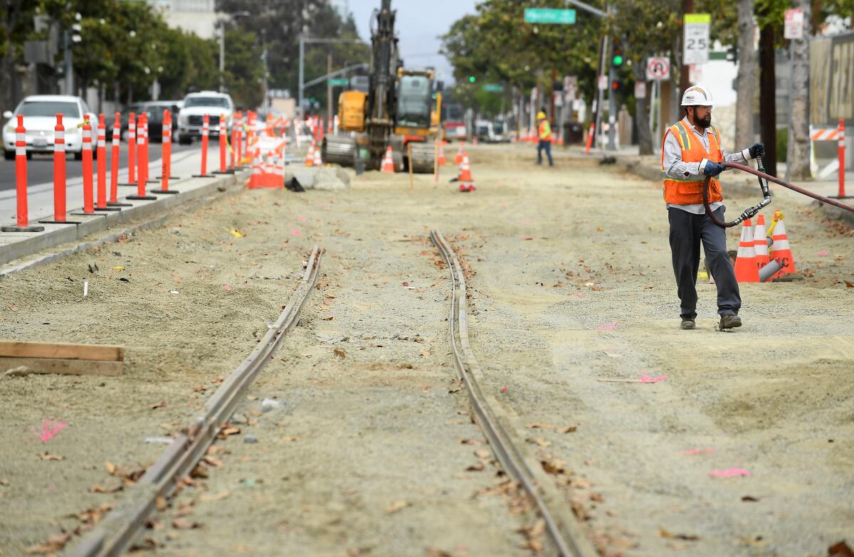 A construction worker walks along train tracks that are being laid. 