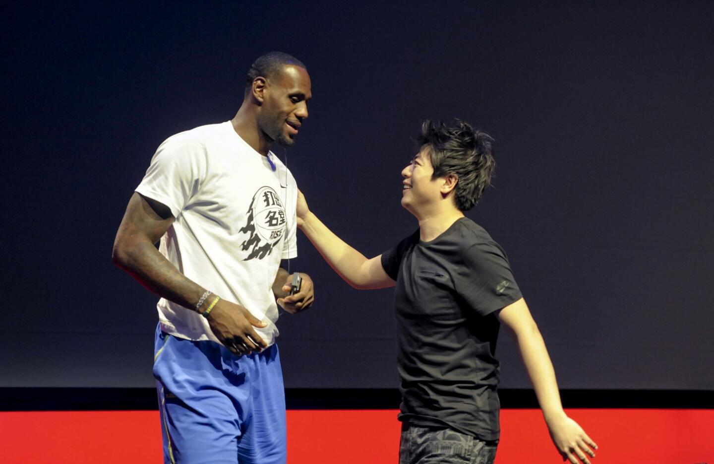 NBA basketball player LeBron James (L) of Cleveland Cavaliers smiles at Chinese pianist Lang Lang as he meets his fans during his trip in Beijing July 21, 2014.