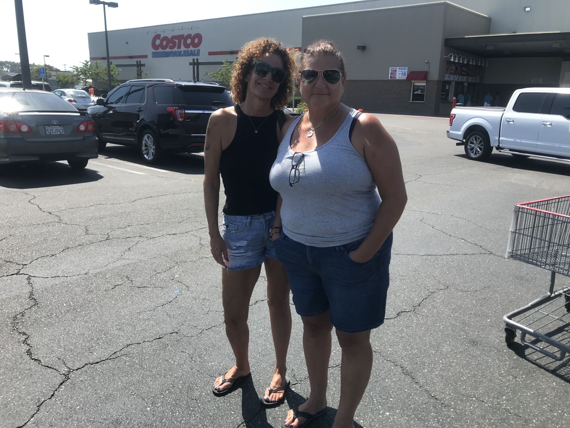 Two women stand in a parking lot.