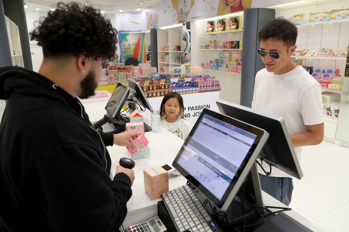 Ocean Hou and her father, Yufei, look on as employee Roman Rivera rings up a total at Pop Mart.