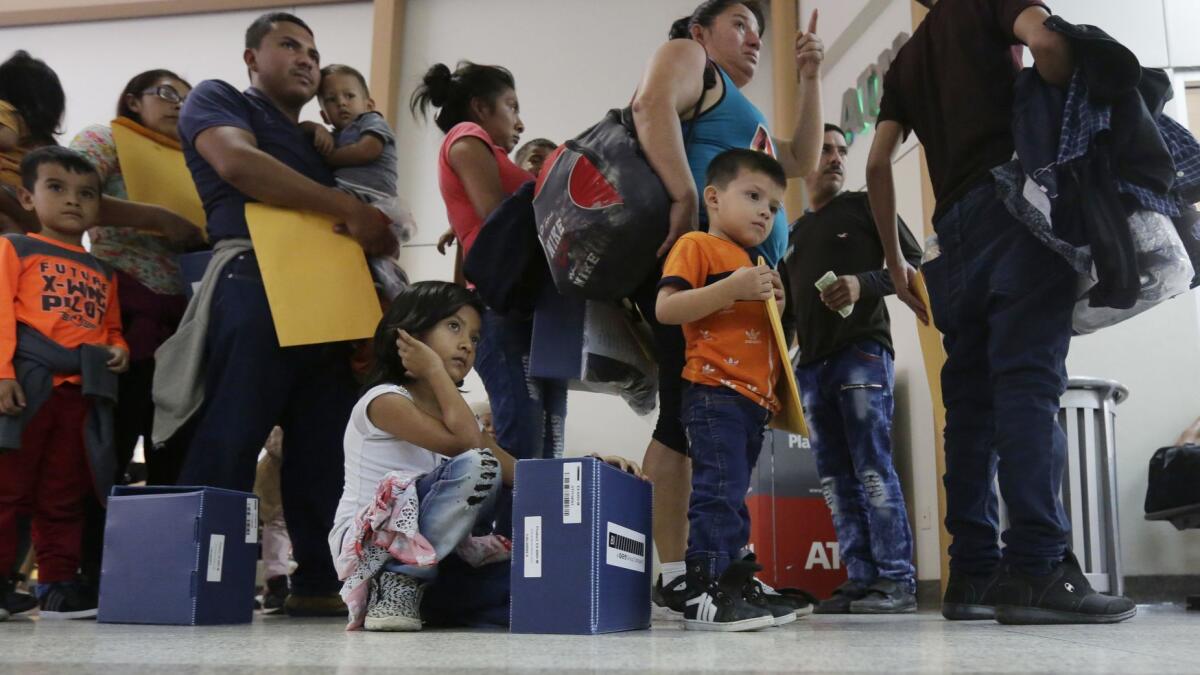 Immigrant families seeking asylum wait in line at a bus station after they were processed and released by U.S. Customs and Border Protection on Friday.