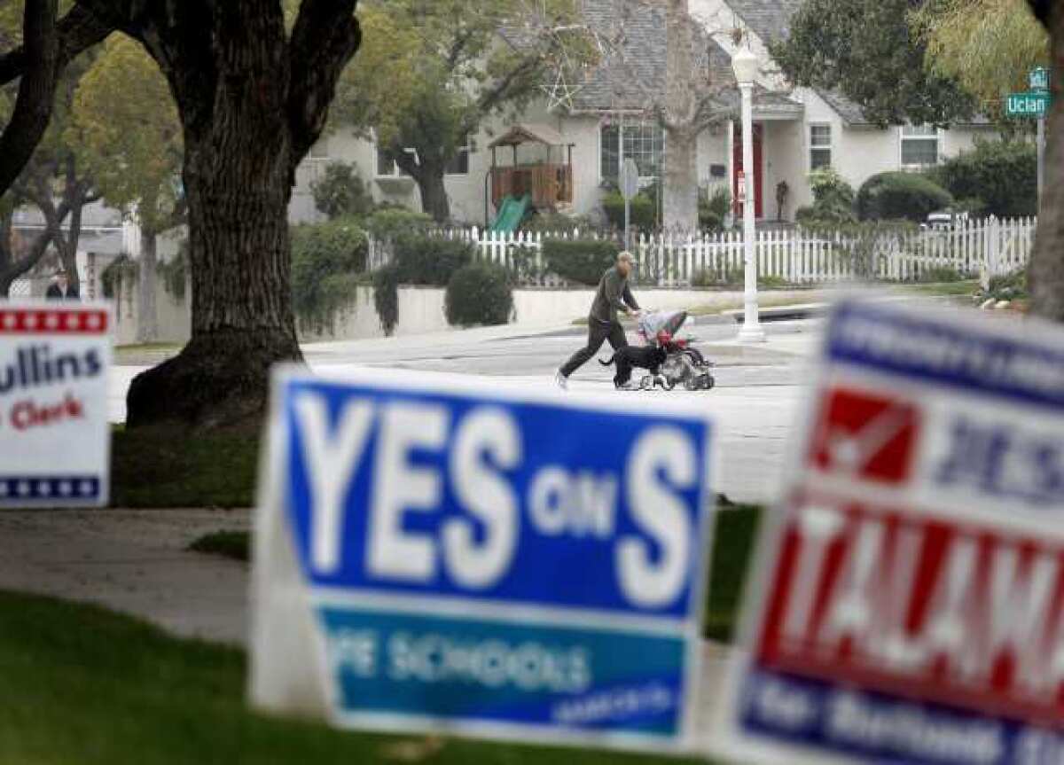 A walker is seen in the background of election signs in the 1500 block of 6th St. in Burbank.