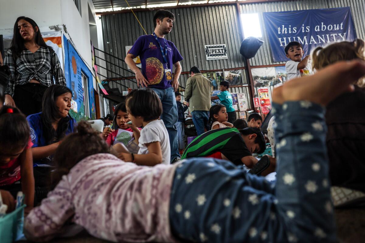 Children pass the time in a crowded area at a migrant shelter.
