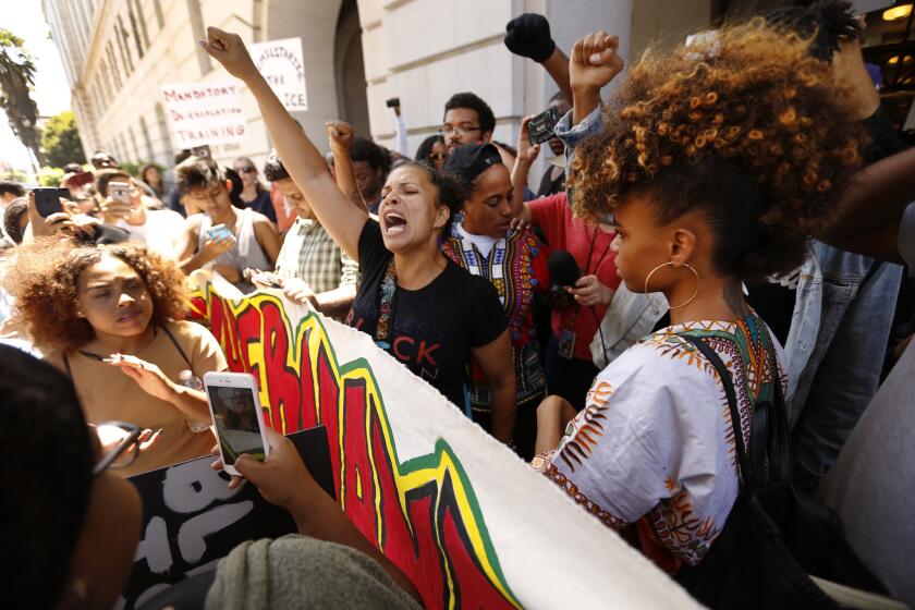 Melina Abdullah, a Cal State Los Angeles professor affiliated with the Black Lives Matter movement, center, chants after she is released by police after being detained inside Los Angeles City Hall.