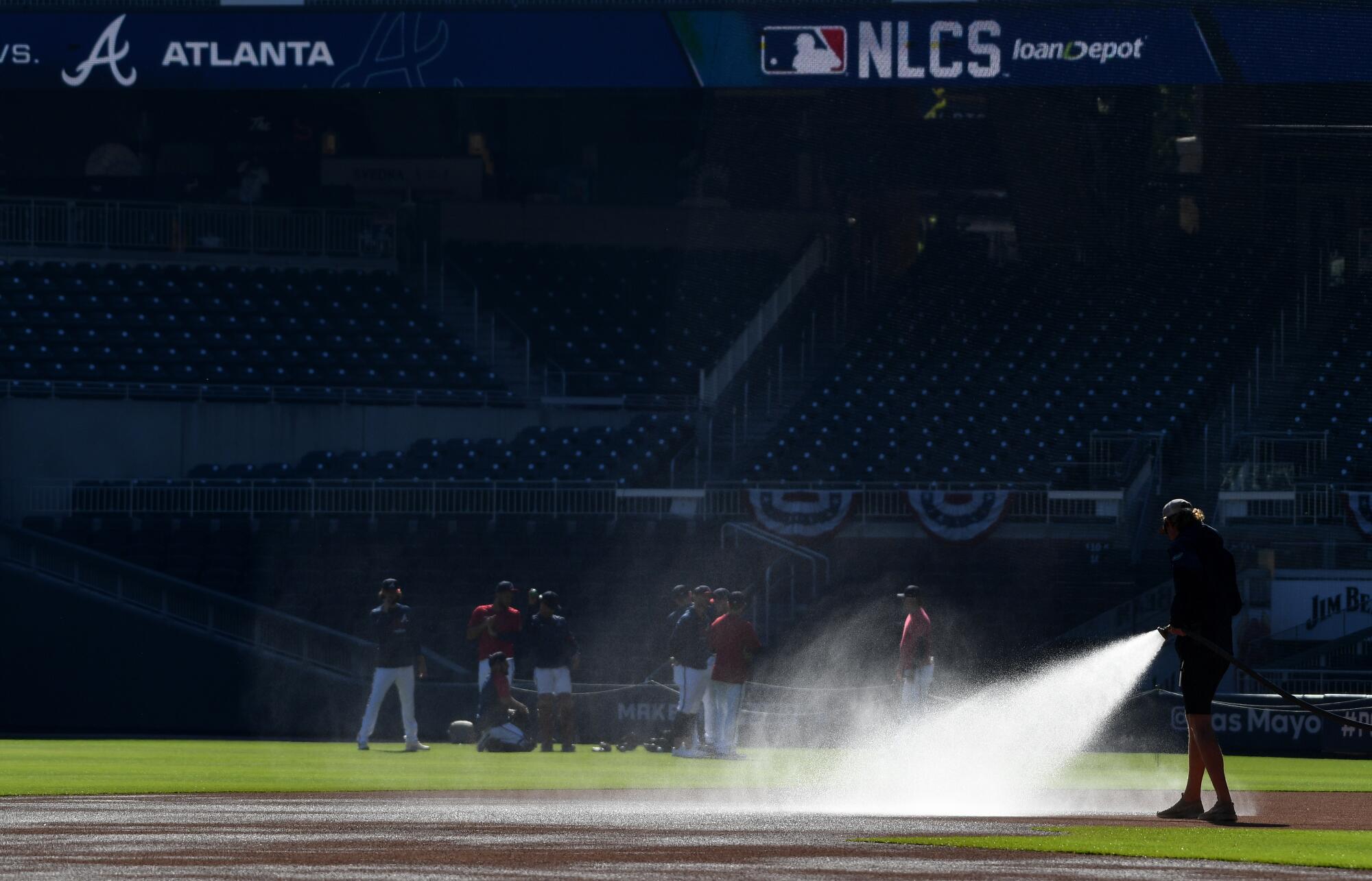 The grounds crew waters the infield before the Los Angeles Dodgers play the Atlanta Braves.