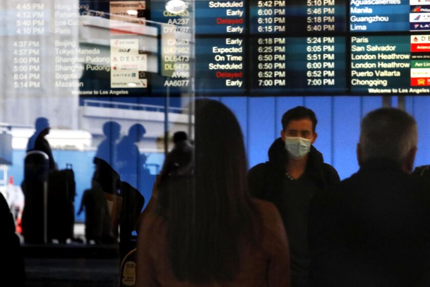LOS ANGELES CA - FEBRUARY 8, 2020 - A traveler wears a mask in fear of the coronavirus while arriving at the Tom Bradley International Terminal at Los Angeles International Airport in Los Angeles on February 8, 2020. (Genaro Molina / Los Angeles Times)