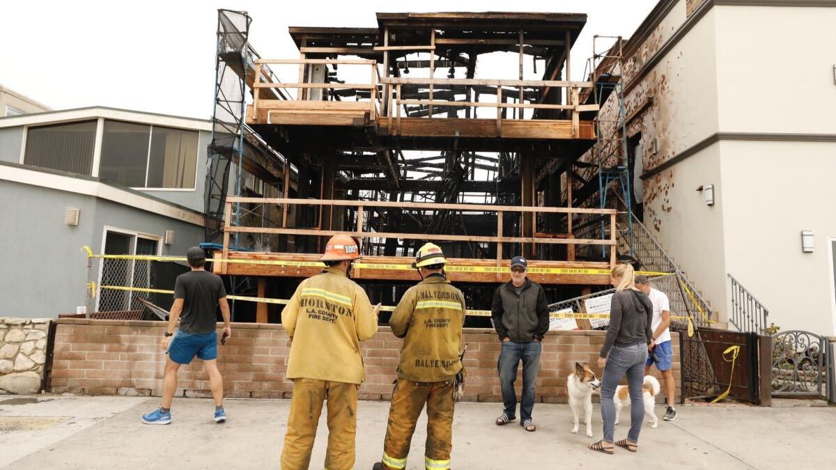 L.A. County fire officials inspect a three-story house under construction that was destroyed by fire in the 800 block of the Strand in Hermosa Beach.