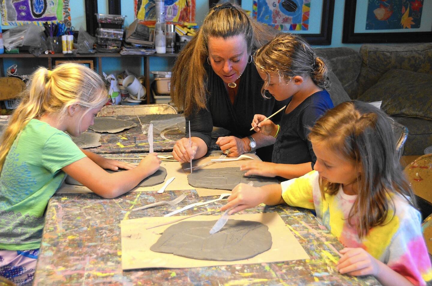 Lisa Albert helps kids carve a leaf pattern into clay in her Saturday morning art class at Albert's art studio.