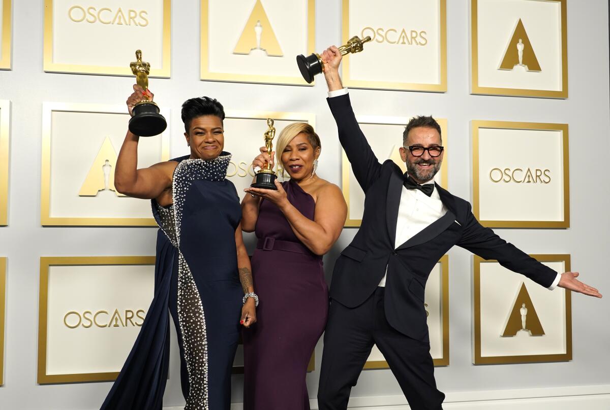 Two women and a man pose with their Oscar statuettes held high.