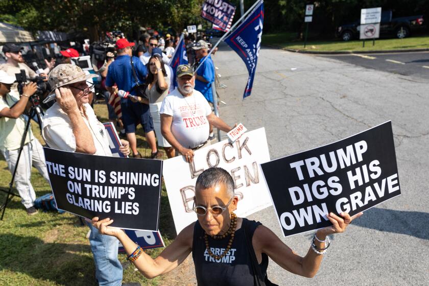 A counter protester waves anti-Trump signs outside the Fulton County Jail ahead of his expected arrival on August 24, 2023, in Atlanta, Georgia. Former US President Donald Trump and 18 others were given until August 25, 2023 to surrender at the courthouse after being indicted on 41 counts related to their efforts to overturn the 2020 US Presidential election. (Photo by Christian MONTERROSA / AFP) (Photo by CHRISTIAN MONTERROSA/AFP via Getty Images)