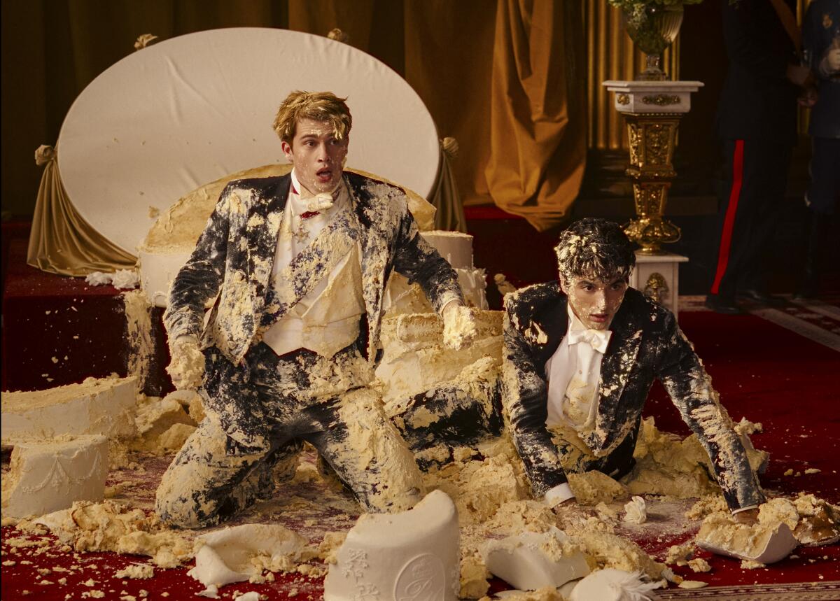 Two young men covered in wedding cake frosting.