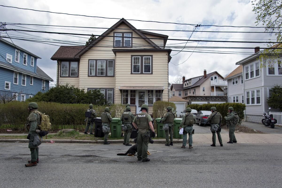 Heavily armed police officers perform house-to-house searches in Watertown, Mass., as they look for one of two suspects in the Boston Marathon bombings.