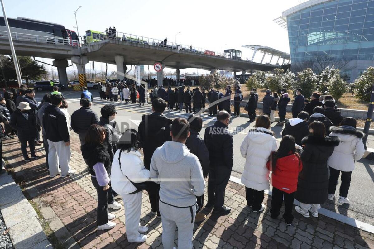 People stand at a memorial altar at an airport in Muan, South Korea.