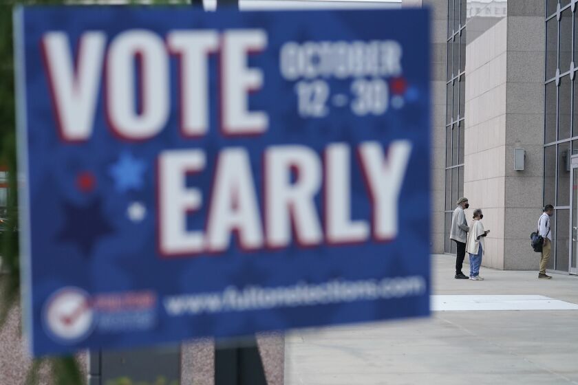 A line forms outside of the State Farm Arena for early voting on Monday, Oct. 12, 2020, in Atlanta. (AP Photo/Brynn Anderson)