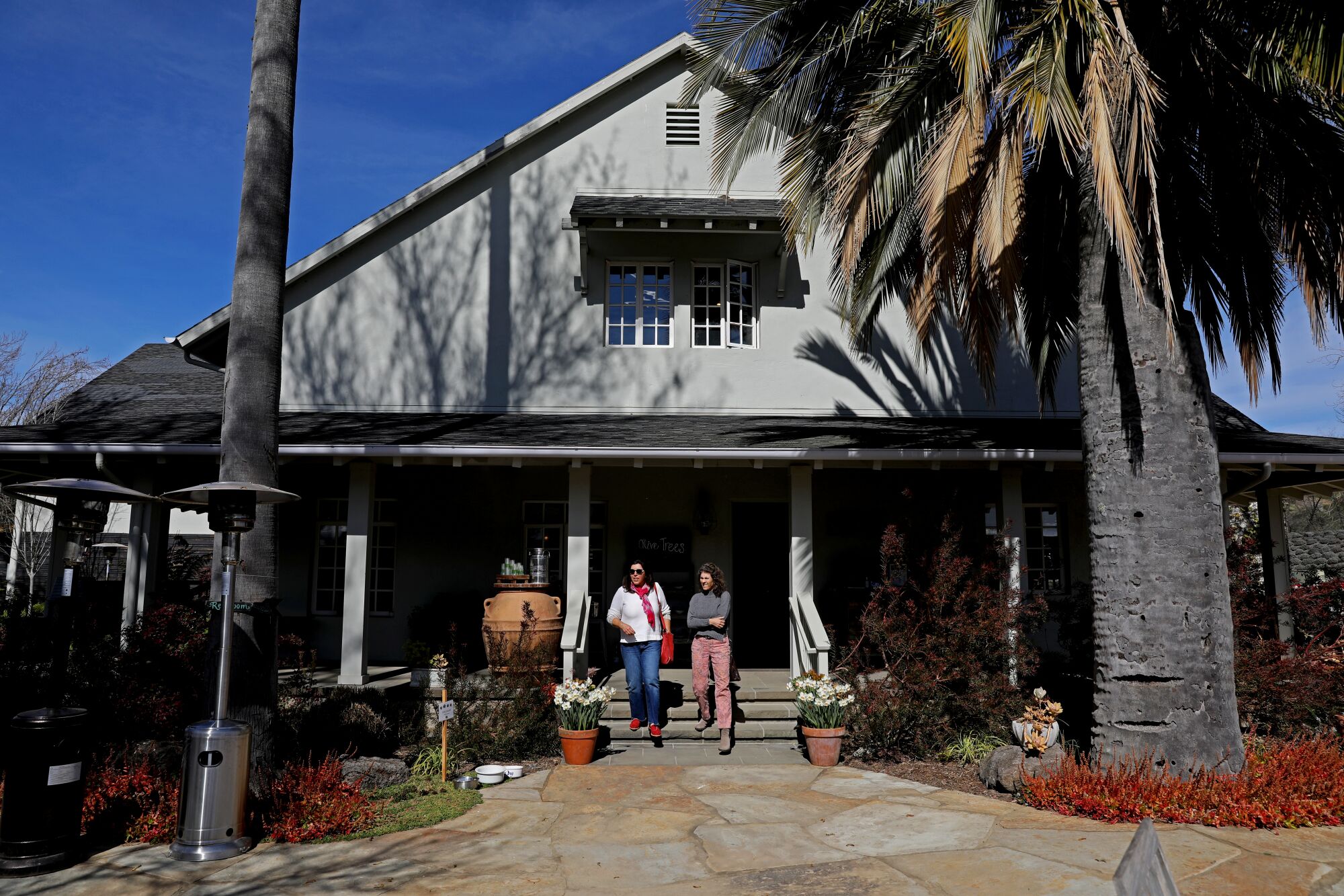 People walk down the front steps at a house used as an olive oil tasting room. 