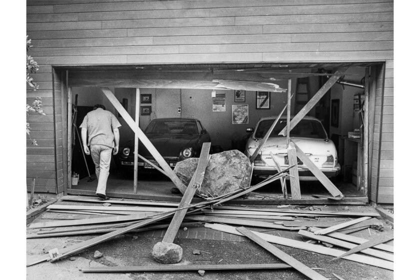 March 24, 1983: Robert Tellier, owner of a home on 19700 block of Pacific Coast Highway, enters the garage where a boulder crashed through the door, damaging both cars.