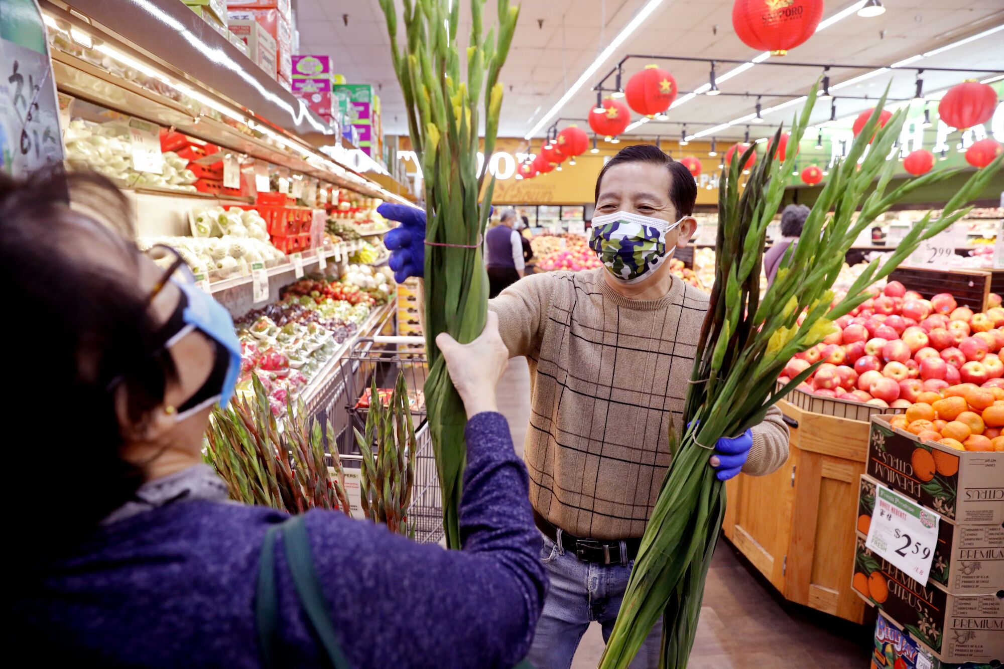 Produce manager Peter Dao, right, helps a customer select fresh gladiolus flowers at the Great Wall Supermarket.