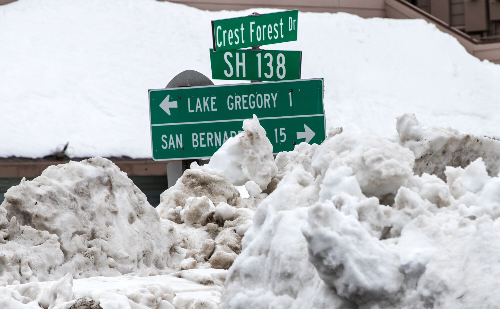 Street signs are barely visible above tall piles of snow off Highway 138 in Crestline.