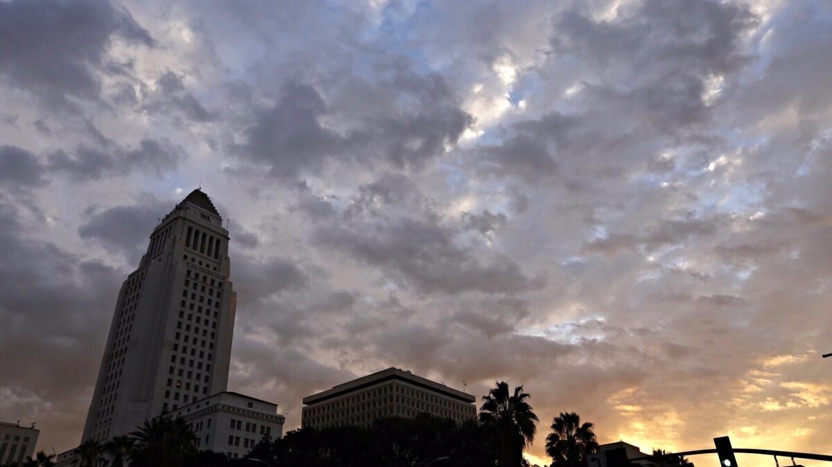 The sun rises over City Hall in downtown Los Angeles on Friday as clouds move into the L.A. Basin with a threat of rain as a storm front promises light rain for parts of the Southland.