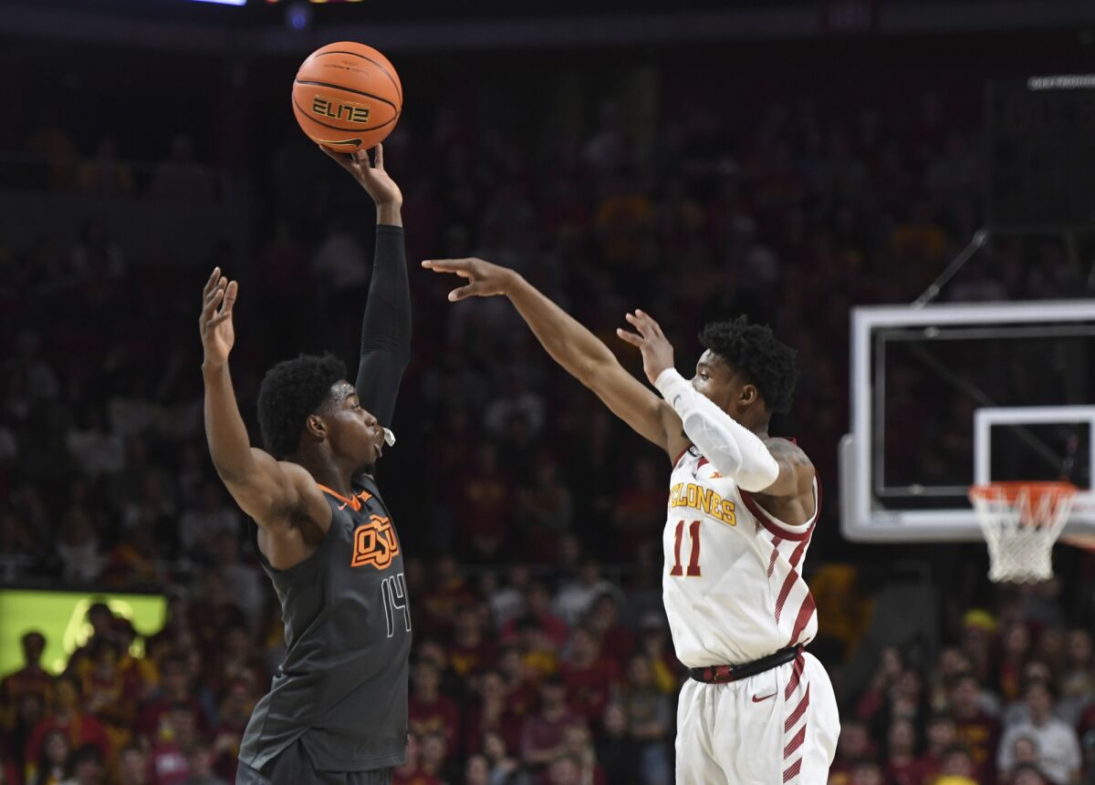 Oklahoma State's Bryce Williams (14) blocks the ball as Iowa State guard Tyrese Hunter (11) passes during the first half of an NCAA college basketball game Wednesday, March 2, 2022, in Ames, Iowa. (Nirmalendu Majumdar/Ames Tribune via AP)