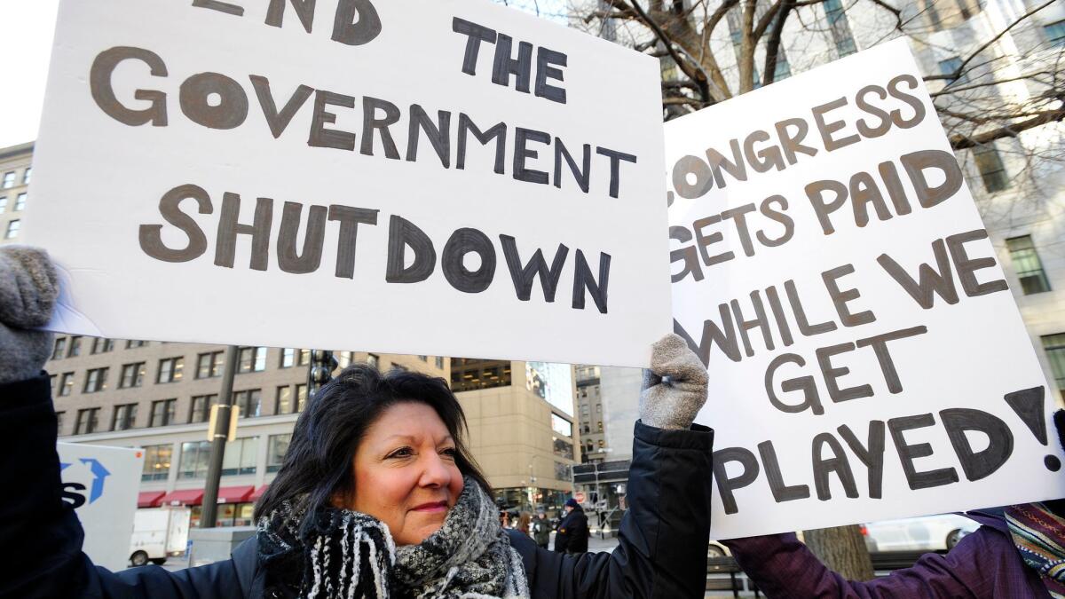 EPA employee Rosanne Sawaya-Obrien holds her sign during a rally and protest by government workers and concerned citizens against the government shutdown on Friday at Post Office Square near the Federal building, headquarters for the EPA and IRS in Boston.