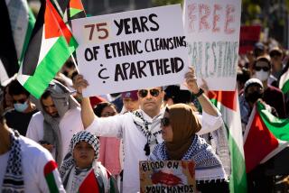 Los Angeles, CA - October 14: Thousands of pro-Palestinian supporters march down Wilshire Boulevard toward the Federal Building, in Los Angeles, CA, Saturday, Oct. 14, 2023. A man holds up a handmade sign, with the words, "75 Years of Ethnic Cleansing & Apartheid." (Jay L. Clendenin / Los Angeles Times)