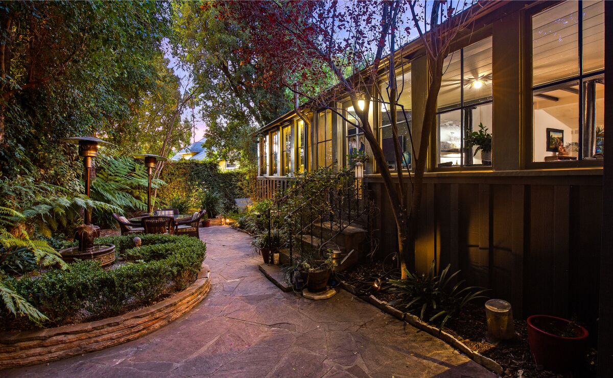 Lush landscaping surrounds a path and the back steps of the home.