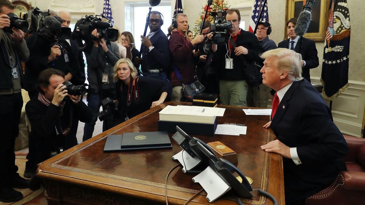 President Trump talks with journalists after signing tax reform legislation in the Oval Office in December 2017.