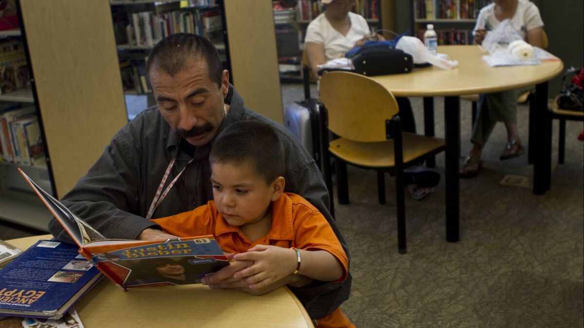 File photo: Cuacuetemoc Montes reads to his son, Raymond, at the Los Angeles Public Library.