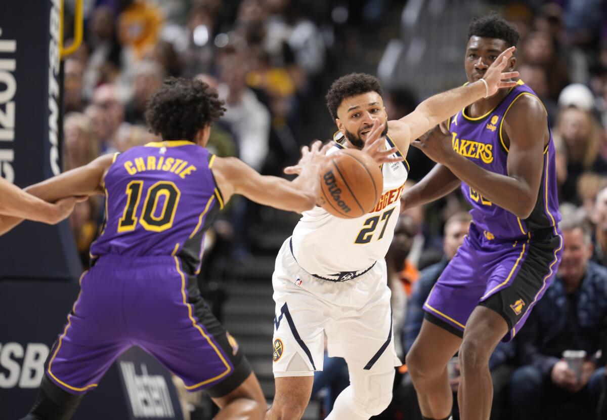 Denver's Jamal Murray, center, fights for control of the ball with Lakers guard Max Christie, left, and center Thomas Bryant.
