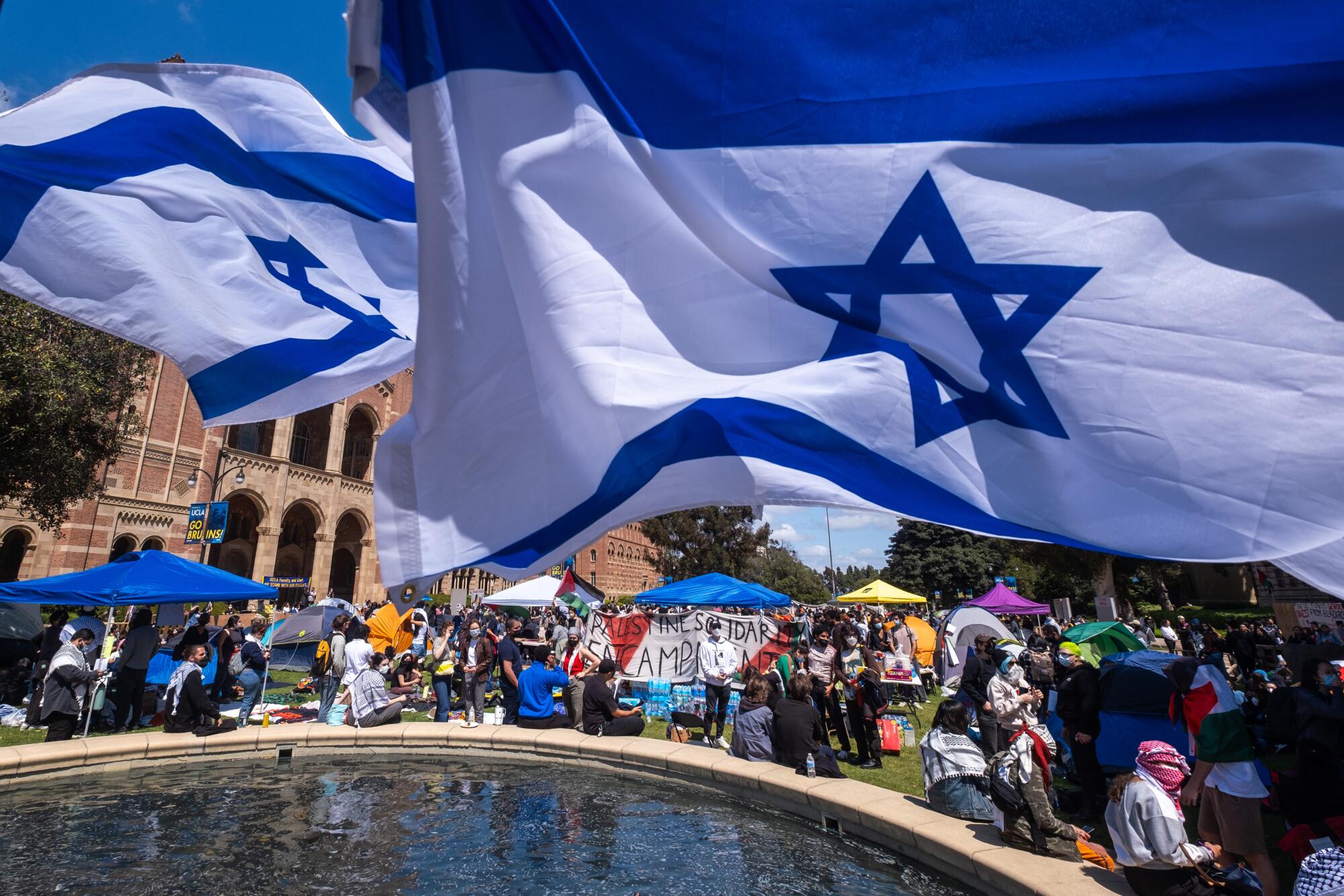 Pro-Israeli supporters wave their flags near an encampment set up by pro-Palestine protesters on the campus of UCLA.