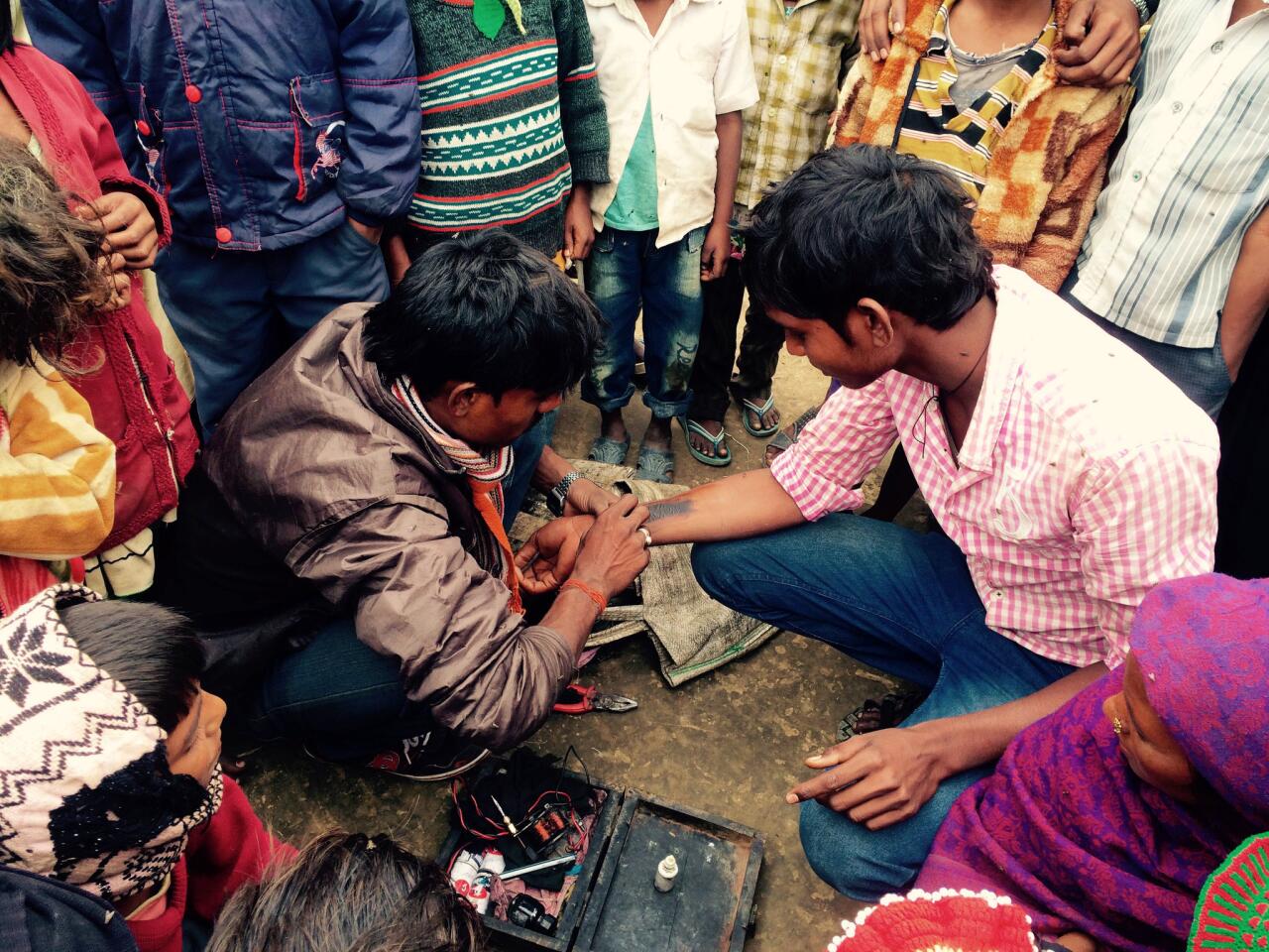 Teenager Deva Reidas gets the name of his wife-to-be tattooed on his forearm as children in their village of Shihokhor, Nepal, look on.