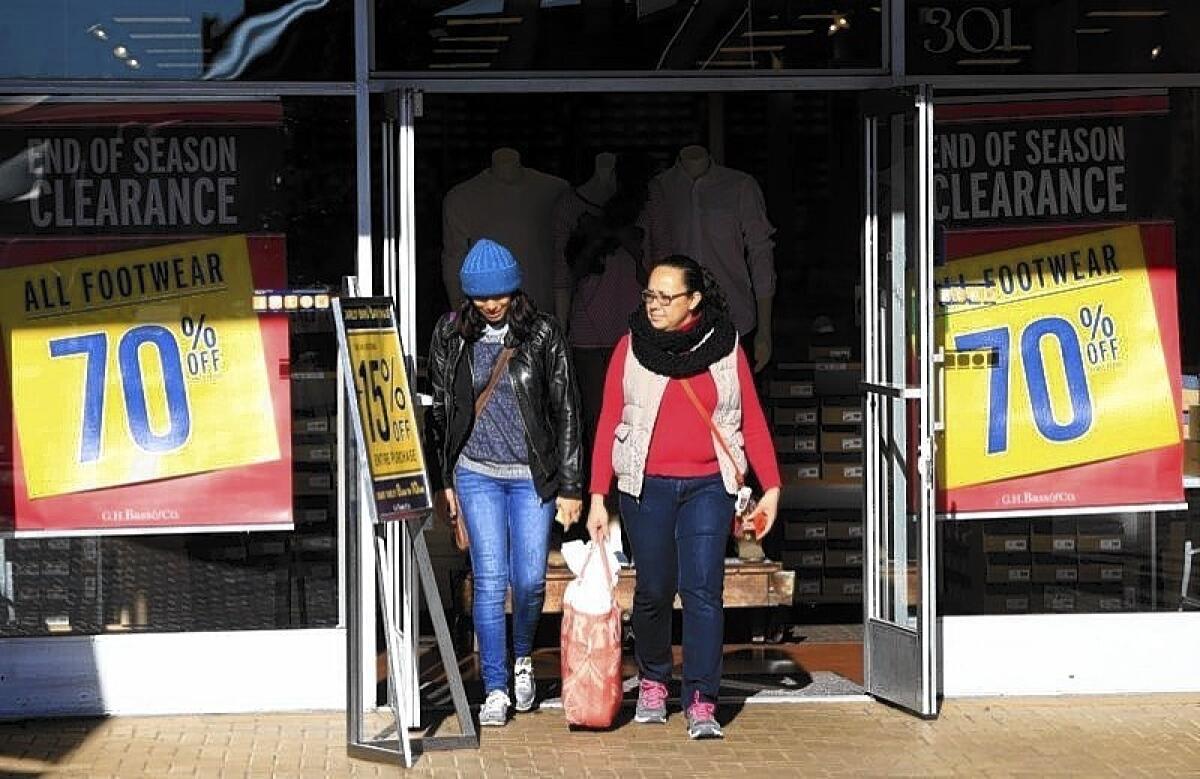 Shoppers exit the Bass store at the Citadel Outlets in Los Angeles where the retailer was offering up to 70% off on Christmas Eve.
