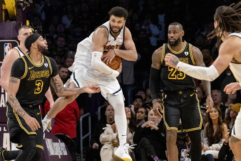 Nuggets guard Jamal Murray leaps to grab a defensive rebound in front of Lakers forwards Anthony Davis and LeBron James.